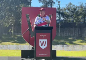 A speaker at a podium with a microphone, addressing the audience at a Western Sydney University event, with the university's logo prominently displayed behind him.